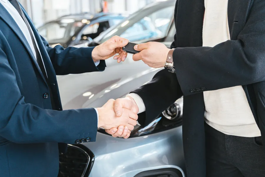 A driver returning car keys to a car rental dealer