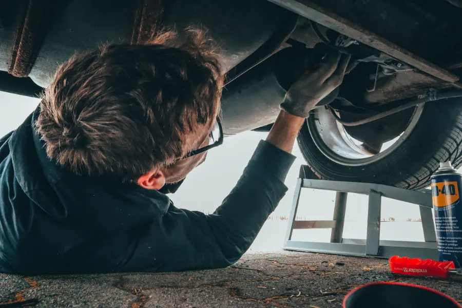 A mechanic under a vehicle fixing it