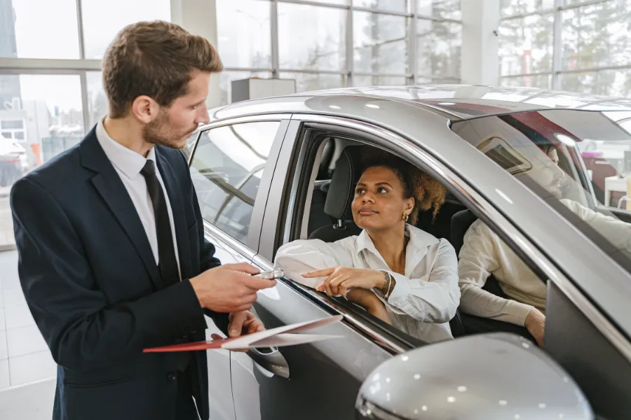 A car dealer handing in keys to a woman
